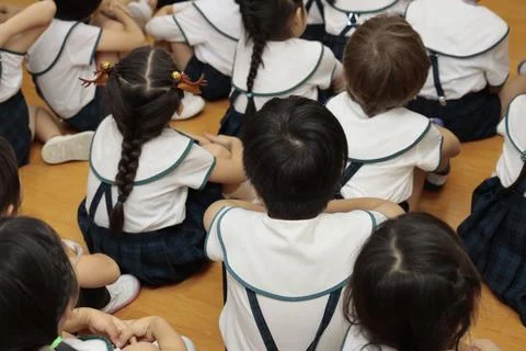Group of elementary school students sitting on the floor in the classroom. Stock Photos