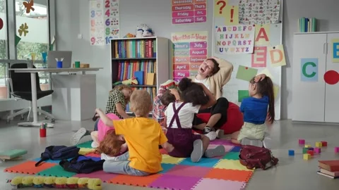 Group of elementary students exercising with teacher sitting on floor in Stock Footage 205017633