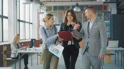 A group of employees walking around the office, lively discussing a business Stock Footage 107526821