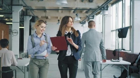 A group of employees walking around the office, lively discussing a business Stock Footage 107528513