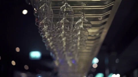 Group of empty wine glasses hanging from metal beams in a bar Video stock 71493537