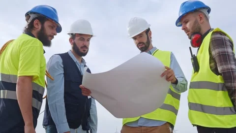 Group of engineers and workers looking at a blueprint s in a windmill park. Stock Footage 198883595