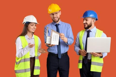 Group of engineers with house model and laptop on orange background Stock Photos