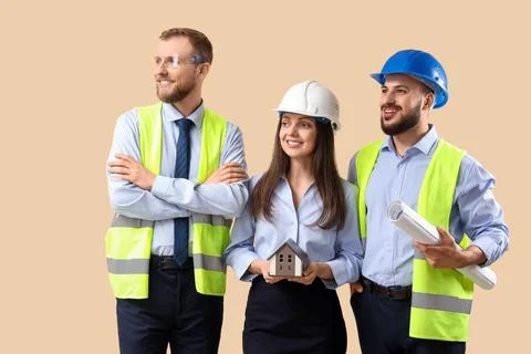 Group of engineers with house model on beige background Stock Photos