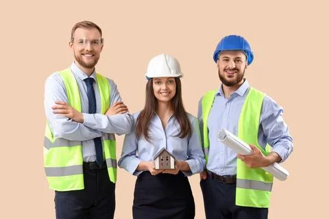 Group of engineers with house model on beige background Stock Photos