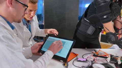 Group of engineers studying work of kinetic suit. Video stock 97671989