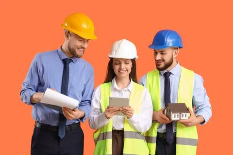 Group of engineers with tablet computer and house model on orange background Stock Photos