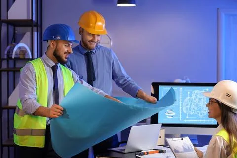 Group of engineers working with house plan in office at night Stock Photos