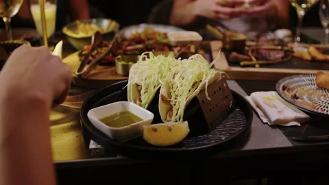 Group Enjoying Dinner With Tacos and Shared Plates at Restaurant Table Stock Footage 342285839