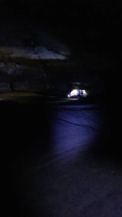 Group enters dark cave with flashlights, exploring rocky tunnel full adventure Video stock 310142909