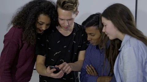 Group of excited adolescents looking at one mobile phone 動画素材 74617997