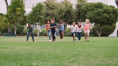 Group Of Excited Children Playing With Friends And Running Across Grass Playing Stock Footage