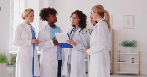 Group of female doctors in lab coats standing in clinic, discussing patient test Stock Footage 312085558