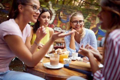 A group of female students are listening to a female friend telling a story i Stock Photos
