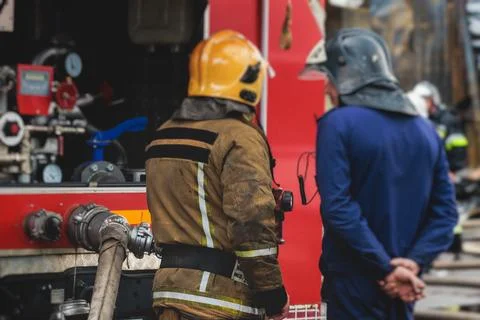 Group of fire men in protective uniform during fire fighting operation in t.. Stock Photos