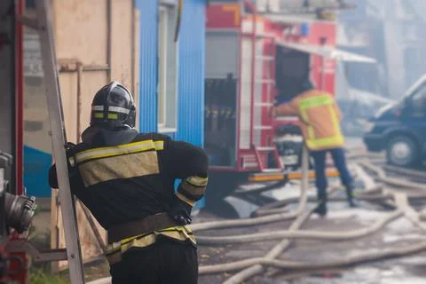 Group of fire men in protective uniform during fire fighting operation in t.. Stock Photos