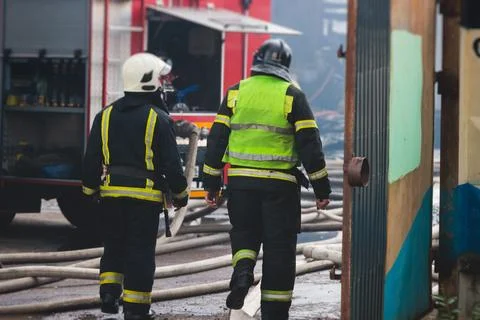 Group of fire men in protective uniform during fire fighting operation in t.. Stock Photos