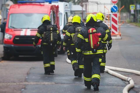Group of fire men in protective uniform during fire fighting operation in t.. Stock Photos