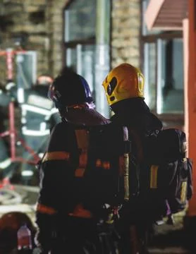 Group of fire men in protective uniform during fire fighting operation in t.. Stock Photos
