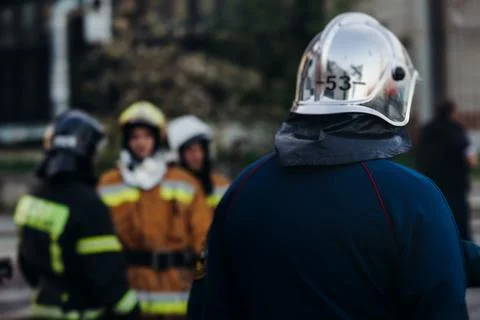 Group of fire men in uniform during fire fighting operation in the city str.. Фото