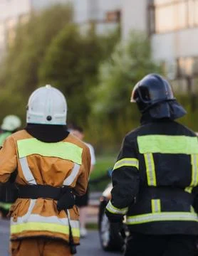 Group of fire men in uniform during fire fighting operation in the city str.. Stock Photos