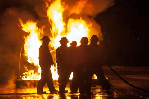 Group of firefighters hosing down burning tank durning firefighting exercise Stock Photos