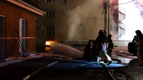 Group of firefighters working on watering a window fire at night Stock Footage 125454355