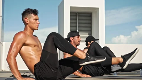 Group of fit athletic men doing bicycle crunch core body workout on rooftop Stock Footage 143455772