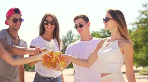 Group of five attractive people clinks with bottles of beer at coast Vídeos de archivo 67349122
