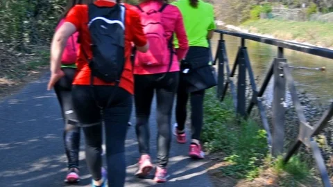A group of five girls walking quickly along a street near the Naviglio of Milan Stock Footage 107719662