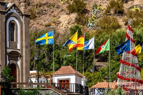 A group of flags are hanging from a tree in front of a church Stock Photos