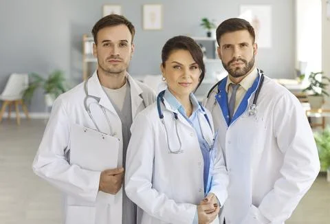 Group of focused professional doctors standing together in medical office and Stock Photos
