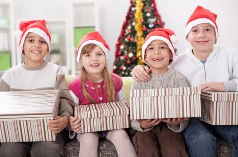 Group of four children in Christmas hat with presents Stock Photos