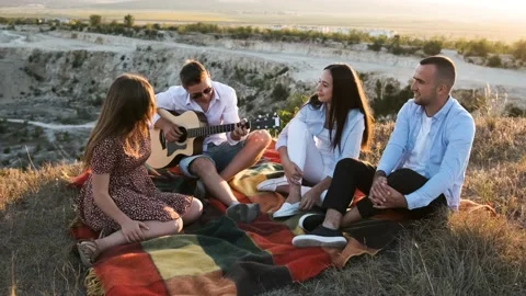 Group of four friends having fun at the summer picnic. Man playing at the guitar Stock Footage 138740710