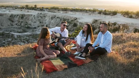 Group of four friends having fun at the summer picnic. Man playing at the guitar Stock Footage 138740913