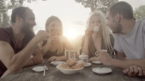 Group of four happy men and women friends smile, laugh and drink coffee Stock Footage