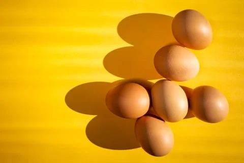 Group of fresh eggs on the table isolated on yellow background. Easter concep 스톡 사진