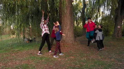 Group of friendly active people with children and grandmother ride swing in Stock Footage 155595774