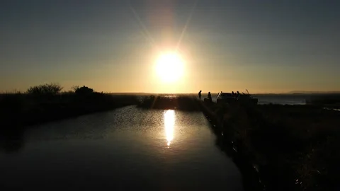 Group of friends and 2 cars silhouetted against a lake sunse Stock Footage