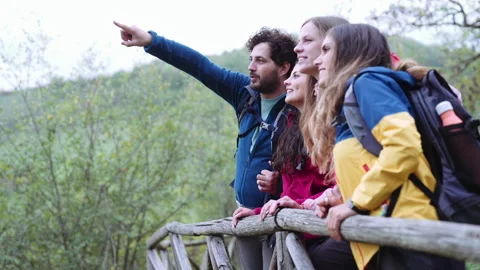 Group of friends are taking a break during a hike while they are looking at view Stock Footage 240983296