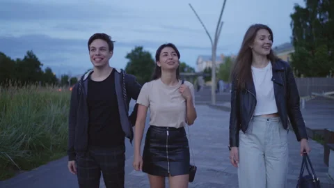 A group of friends are walking,the guy points his finger at something,they laugh Stockbeeldmateriaal 202313079