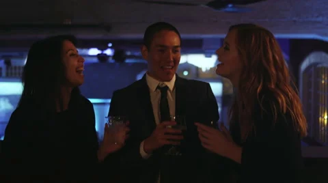 A group of friends in the balcony of a nightclub talk and toast their drinks Stock Footage