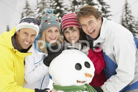 Group Of Friends Building Snowman On Ski Holiday In Mountains Stock Photos