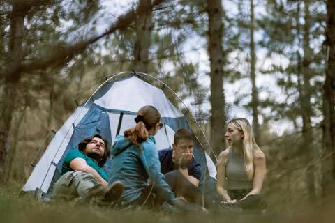 Group of friends camp in forest setting, sharing stories and enjoying nature Stock Photos