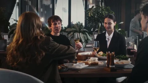 Group of friends chatting at a table in an upscale cafe with food and drinks Stock-Footage 314577454