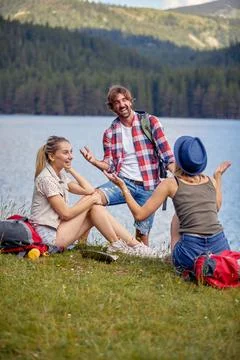 A group of friends chatting while taking a rest at the lake during mountain.. Stock Photos