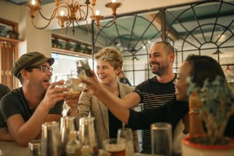 Group of friends cheering with drinks in a trendy bar Stock Photos