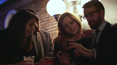 A group of friends in a club looking at pictures on a cell phone Stock Footage