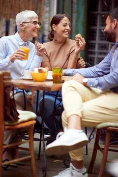 A group of friends of different generations talking while they have a drink i Stock Photos
