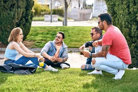 Group of friends drinking refreshments and hanging out in the park in summer. Foto stock